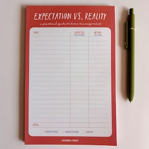 May include: A red notepad with the text "EXPECTATION VS. REALITY" and a practical guide to time management. The notepad has columns for tasks, expected time, and actual time. A green pen rests beside the notepad.