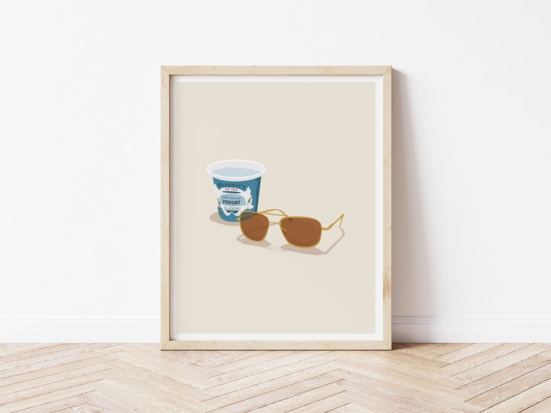 Puede incluir: Una impresi&oacute;n enmarcada con una ilustraci&oacute;n minimalista de un recipiente de yogur azul y gafas de sol marrones sobre un fondo beige.