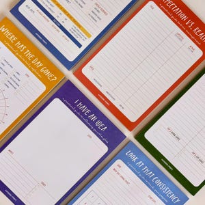 May include: A collection of colorful, rectangular notepads with various prompts and titles. The pads feature titles like "Where Has The Day Gone?" and "I Have An Idea." Each pad has a different color border, including blue, orange, red, purple, and green.