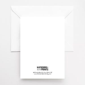 May include: A white greeting card with a matching envelope. The card has the text "KATIEBIRD PRINTS" and contact information printed in black at the bottom. The background is a solid white.