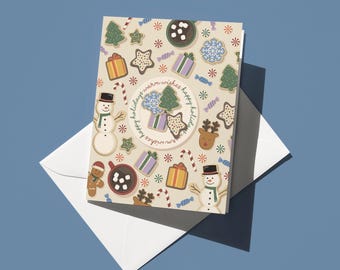 May include: A holiday greeting card with a beige background featuring festive cookie illustrations, including snowmen, gingerbread men, and presents. The card is accompanied by a white envelope and includes the text "happy holidays warm wishes".