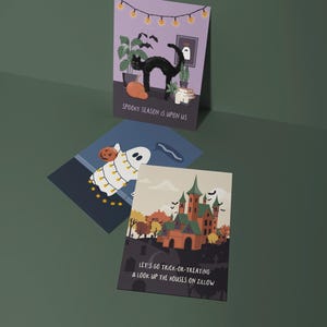 May include: Three Halloween-themed greeting cards. One card features a black cat, pumpkin, and the text "SPOOKY SEASON IS UPON US." Another shows a ghost with a pumpkin and string lights. The third card displays a haunted house and the text "LET'S GO TRICK-OR-TREATING & LOOK UP THE HOUSES ON ZILLOW."