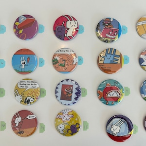 May include: A collection of 20 round button pins featuring colorful cartoon illustrations and text. The buttons are arranged in a grid on a white background. Some of the text on the buttons includes "Nugget", "Some Carrots", "Dump, King Viking", "Mega Mole Girl", and "Princess Party".