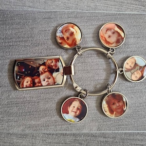 May include: A silver keyring with six round photo charms. The charms feature pictures of children. The keyring is a great way to keep memories close.