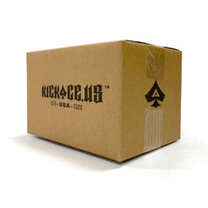 May include: A brown cardboard box with the text "KICKACE.US" and "ESTD - USA - 2020" printed on the front. A black spade symbol is printed on the side of the box.