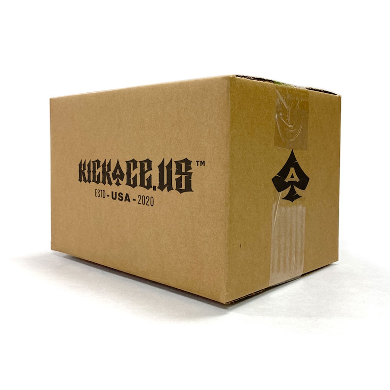 May include: A brown cardboard box with the text "KICKACE.US" and "ESTD - USA - 2020" printed on the front. A black spade symbol is printed on the side of the box.