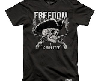 May include: Black t-shirt featuring a skull wearing a pirate hat and holding two crossed pistols. The text "FREEDOM IS NOT FREE" is printed below the skull.