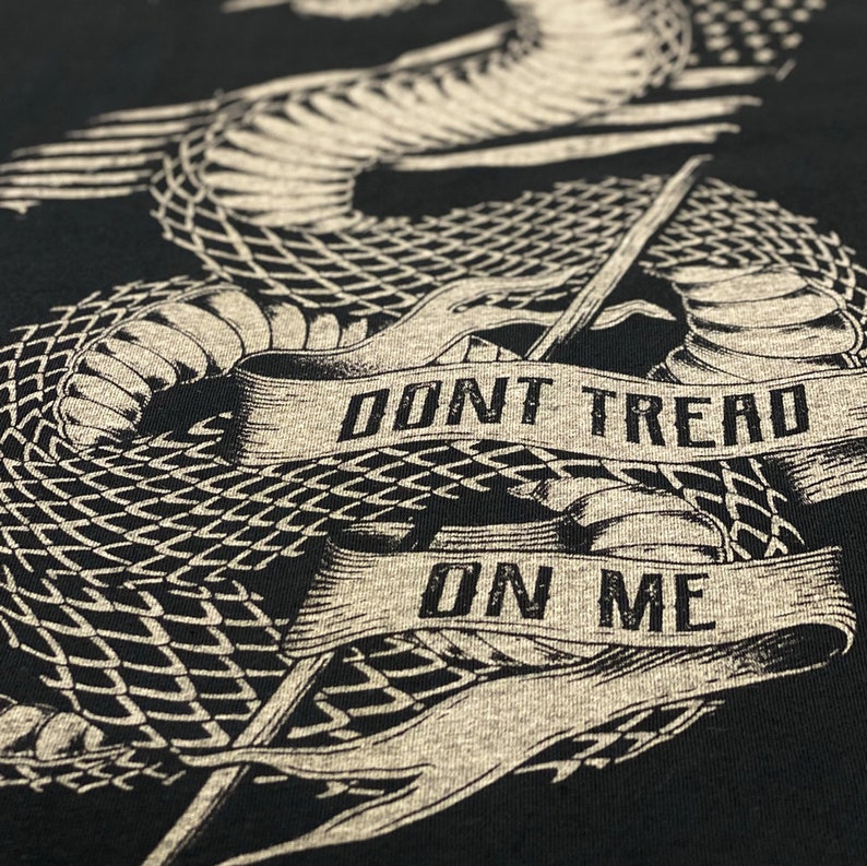May include: A black t-shirt featuring a graphic of a coiled rattlesnake with the words "Don't Tread On Me" on a banner.