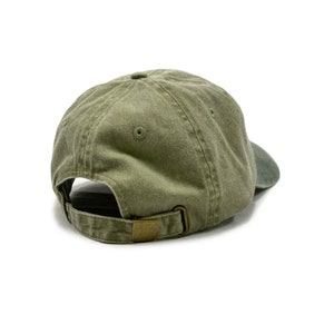 May include: A green cotton baseball cap with a brown adjustable strap. The cap is viewed from the back.
