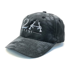 May include: A black camouflage baseball cap with a white embroidered design that says "2A -1791" with two stylized rifles.