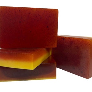 Peut inclure: Quatre barres de savon artisanal, empilées les unes sur les autres. La barre du haut est rouge unie, la deuxième barre est une barre à deux couches rouge et jaune, la troisième barre est une barre à deux couches rouge et jaune, et la barre du bas est une barre à deux couches rouge et jaune.