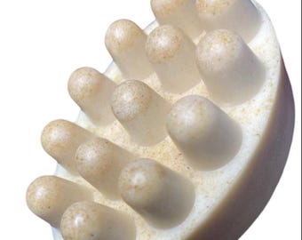May include: A white oval-shaped soap bar with a textured surface. The soap has multiple raised bumps on the surface.