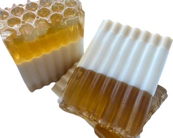 May include: Two bars of handmade soap with a honey and white layered design. The top layer of the soap is a honeycomb pattern.