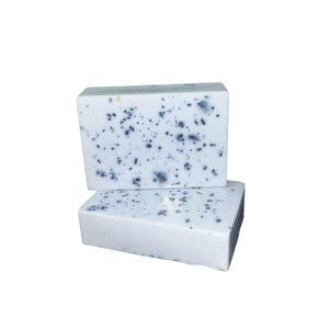 May include: Two bars of white soap with blue flecks throughout. The soap is stacked on top of each other.