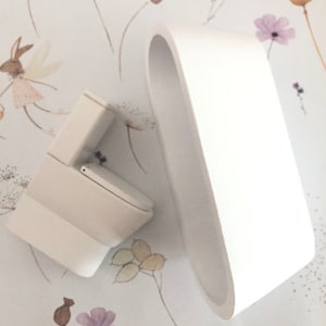 May include: White miniature bathtub and toilet set. The bathtub is oval shaped and the toilet is a standard design. Both are made of white ceramic.