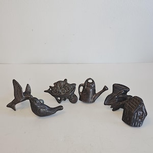 Peut inclure: Ensemble de cinq boutons de meubles décoratifs en fonte. Les boutons représentent un oiseau en vol, un oiseau perché, une brouette, un arrosoir et un ensemble d'outils de jardinage avec une petite maison.