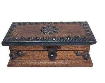 May include: A wooden box with a hinged lid and a metal latch. The box is decorated with metal studs and a floral design. The box is brown and has a rustic appearance.