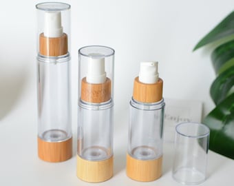 May include: Three clear glass bottles with bamboo caps and pumps. The bottles are different sizes and are arranged in a row from largest to smallest.