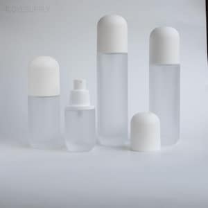May include: A collection of four frosted glass bottles with smooth white rounded caps. Three bottles are tall and cylindrical with caps attached, while one shorter bottle features a white spray pump mechanism without a cap. The text 4LOVESUPPLY is visible.