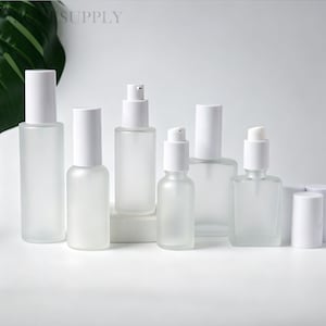 May include: A collection of frosted glass cosmetic bottles with white caps and pump dispensers. The set includes various cylindrical and rectangular shapes, featuring smooth, translucent surfaces and white plastic pump mechanisms for dispensing liquids.