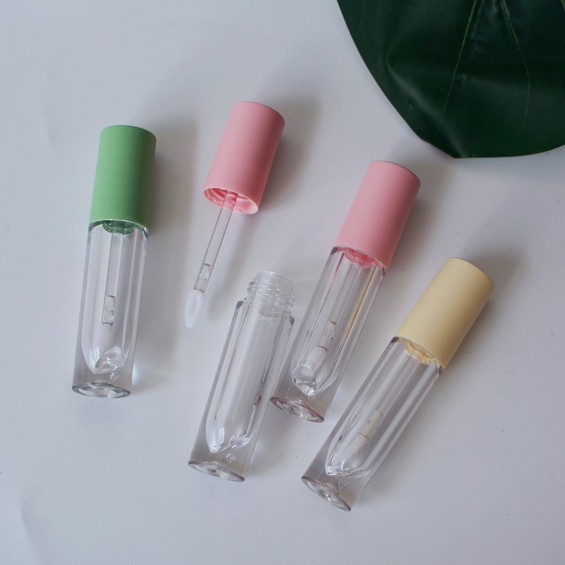 May include: Five clear lip gloss tubes with different colored caps. The caps are green, pink, pink, yellow, and pink. The tubes are all empty.