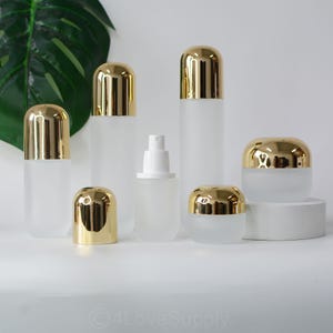 Peut inclure: Ensemble de flacons et de pots en verre givré avec des couvercles dorés. Les flacons et les pots sont de différentes tailles et formes. Les flacons et les pots sont parfaits pour stocker des lotions, des crèmes et d'autres produits de beauté.