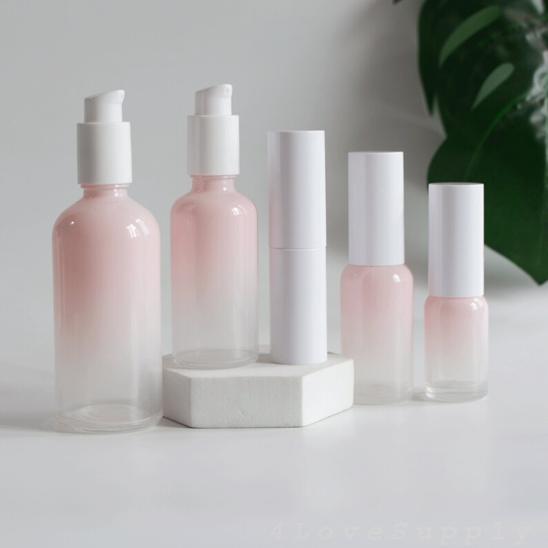 May include: Set of five pink and white glass bottles with pump tops. The bottles are ombre, with a darker pink at the top and fading to white at the bottom.