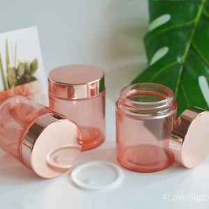 Peut inclure: Trois pots en verre rose gold avec des couvercles rose gold. Les pots sont transparents et ont une finition givrée. Les couvercles sont brillants et ont une finition lisse.