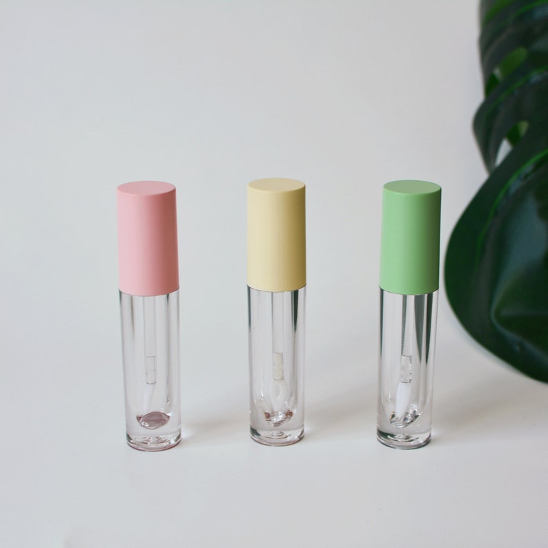 May include: Three clear lip gloss tubes with different colored caps. The caps are pink, yellow, and green.
