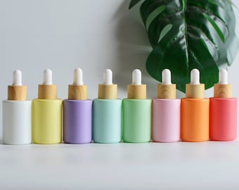 May include: Eight glass dropper bottles with wooden caps in a rainbow of colors, including white, yellow, purple, light green, green, pink, orange, and red.