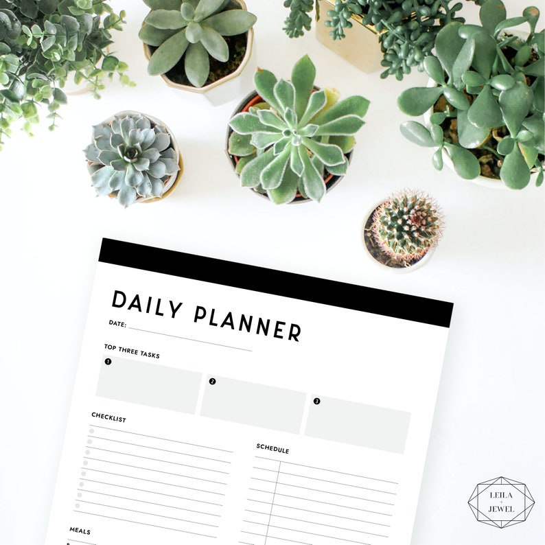 May include: A black and white daily planner with the text "DAILY PLANNER" at the top. The planner has sections for "Top Three Tasks", "Checklist", "Schedule", and "Meals".