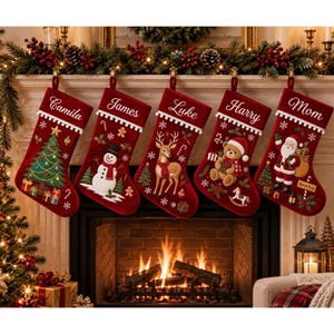 Könnte beinhalten: Fünf tiefrote Weihnachtsstrümpfe aus Samt hängen in einer Reihe, jeder mit einem weißen Umschlag, auf dem die Namen Camila, James, Luke, Harry und Mom gestickt sind. Die Strümpfe sind mit festlichen Applikationen wie Tannenbaum, Schneemann, Rentier, Teddybär und Weihnachtsmann verziert.
