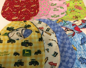May include: A set of ten colorful baby bibs with various patterns, including frogs, monkeys, tractors, and fire trucks. The bibs are made of soft fabric and have a comfortable fit for babies.