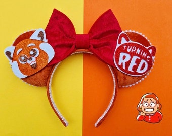 May include: Red and orange mouse ears with a red bow. The left ear features a red panda face with glitter. The right ear features a white circle with the text "Turning Red" in white letters.