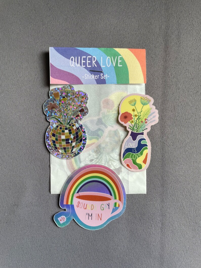 May include: A sticker set with the text "QUEER LOVE" and a rainbow design. The set includes stickers with a disco ball, a vase of flowers, and a teacup with the text "SOUND GAY I'M IN".