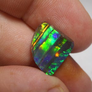May include: A green, blue and orange opal gemstone with a rough, natural cut. The opal has a dark, iridescent sheen.