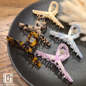 May include: Four tortoise shell hair clips in different designs. The clips are on a black surface.