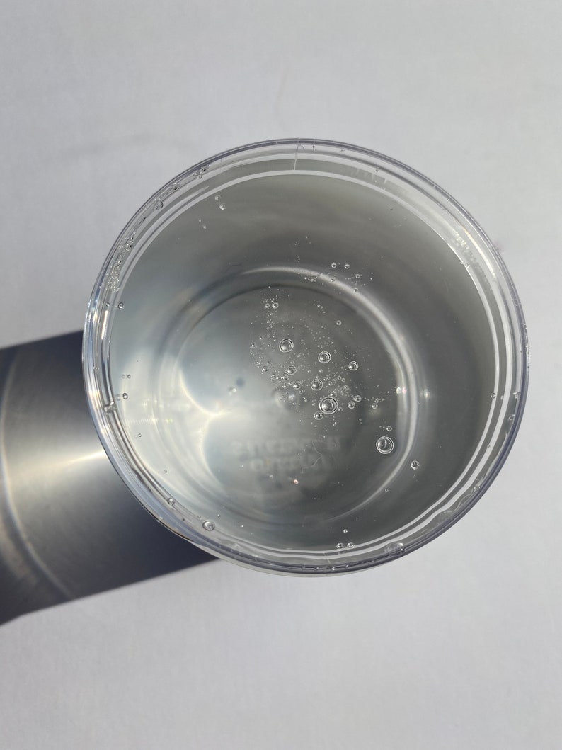 May include: A clear plastic container with a white liquid inside. The liquid has small bubbles throughout.