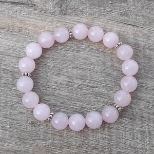 May include: A pink rose quartz bracelet with silver beads. The bracelet is made of round beads and is strung on elastic.