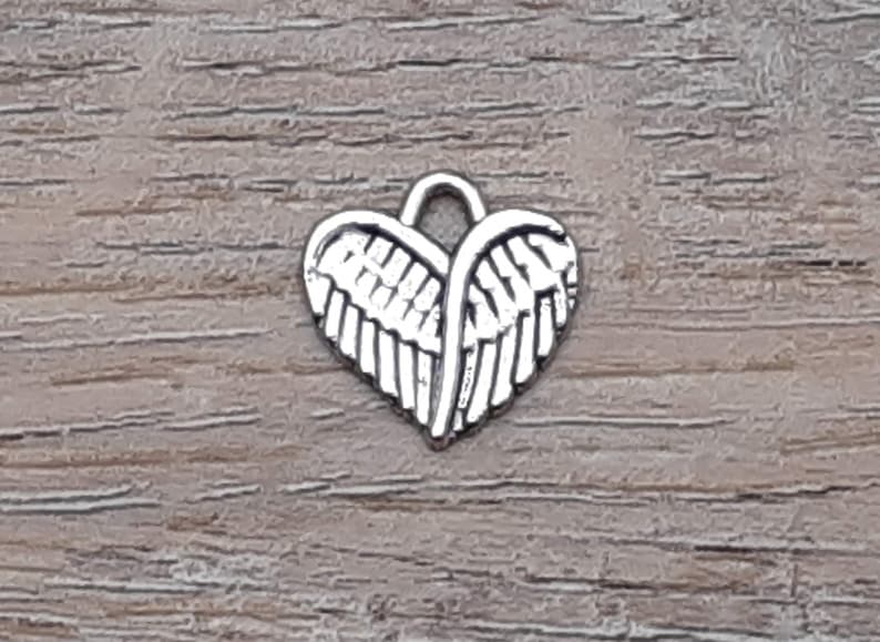 Puede incluir: Encanto de plata en forma de coraz&oacute;n con alas de &aacute;ngel.