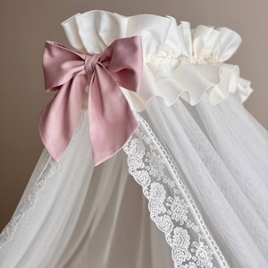 Puede incluir: Dosel blanco con un lazo de satén rosa y ribete de encaje blanco. El dosel está hecho de tela transparente y es perfecto para una cuna de bebé.