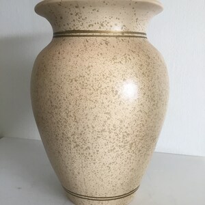 Op de afbeelding: Een grote, crèmekleurige keramische vaas met een gespikkelde afwerking en twee gouden banden rond de boven- en onderkant.