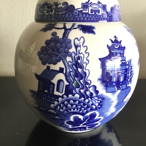 Puede incluir: Un tarro de jengibre de porcelana azul y blanco con tapa. El tarro presenta un diseño tradicional de paisaje chino con una pagoda, árboles y un río.