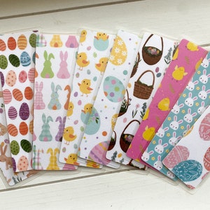 May include: A collection of Easter-themed bookmarks with various designs. The bookmarks feature colorful patterns of Easter eggs, bunnies, chicks, and baskets. Each bookmark has a clear plastic sleeve.