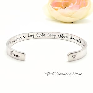 May include: A silver bangle bracelet with the inscription "A mother's hug lasts long after she lets go" and "Mom" engraved on the inside. A small heart is engraved on the other side.