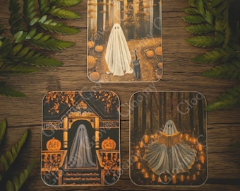 Puede incluir: Tres tarjetas ilustradas con un fantasma blanco en un entorno de bosque. La primera tarjeta muestra al fantasma de pie en un bosque con un gato negro. La segunda tarjeta muestra al fantasma de pie en un porche con una puerta de madera tallada. La tercera tarjeta muestra al fantasma sentado en un círculo de velas, leyendo un libro.