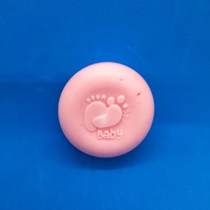 May include: A pink baby soap with a baby footprint and the word "Baby" embossed on it.
