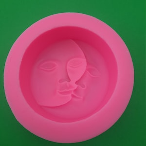 May include: Pink silicone mould with a raised design of two faces, one on top of the other, forming a crescent moon shape.