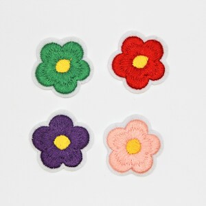 May include: Four embroidered flower patches in different colours: green, red, purple, and pink. Each flower has a yellow centre.