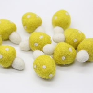 Puede incluir: Un grupo de diez setas de fieltro amarillo con lunares blancos y tallos blancos.